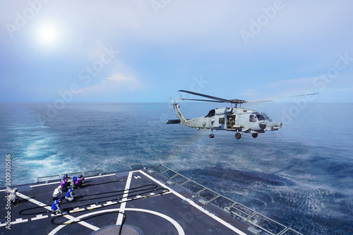 military helicopter flying above the war ship  above the ocean. dangerous during work and safety for work concept.