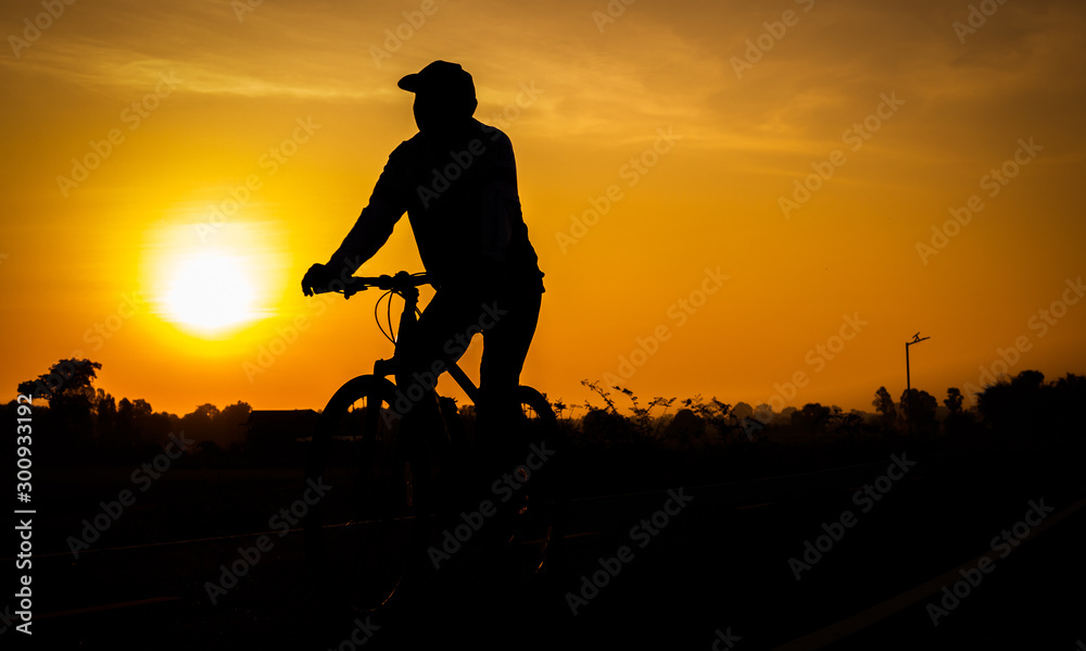 Cyclists on the road backlit at sunrise in the morning.