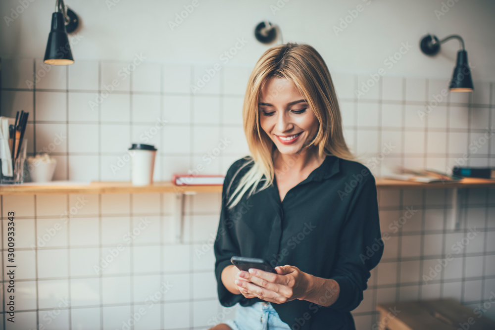 Cheerful Caucasian hipster girl dressed in casual wear phoning via smartphone gadget using public internet connection, happy female blogger smiling while reading received email from follower Cheerful Caucasian hipster girl dressed in casual wear phoning via smartphone gadget using public internet connection, happy female blogger smiling while reading received email from follower
