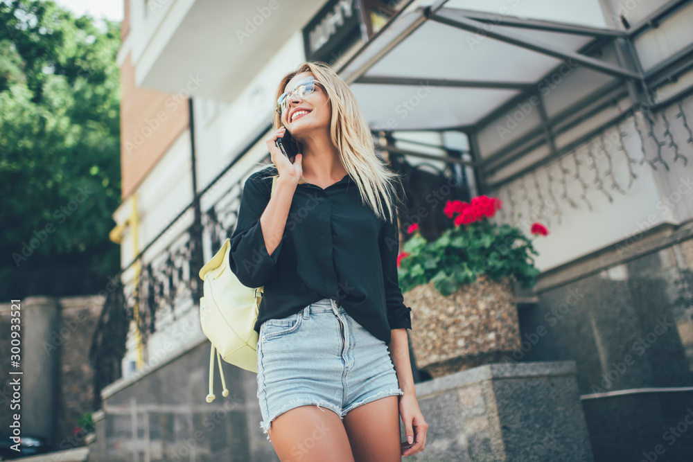 Below view of excited female traveller in casual apparel calling to best friend for sharing impressions about summer holidays, positive hipster girl using roaming connection for international call Below view of excited female traveller in casual apparel calling to best friend for sharing impressions about summer holidays, positive hipster girl using roaming connection for international call