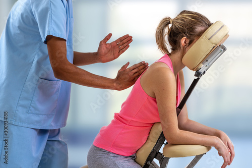 Physiotherapist giving back massage to a patient in the clinic in a massage chair photo