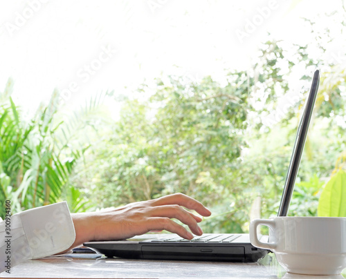 Business Man working on laptop outdoor with white coffee cup in the morning. photo