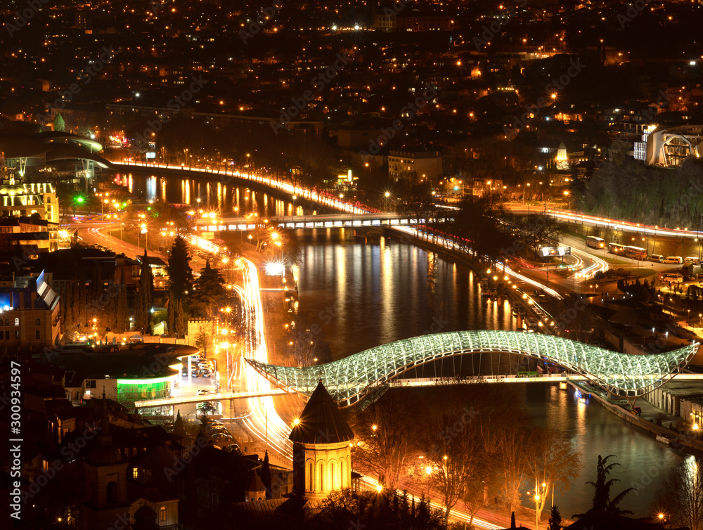 Fototapeta premium Modern glass Bridge of Peace over the Kura river or Mtkvari river in old town Tbilisi, Georgia,beautiful night cityscape from aerial viewpoint