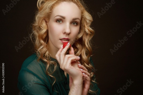 Young girl eats strawberries. Portrait in the studio on a multi-colored background