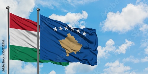 Hungary and Kosovo flag waving in the wind against white cloudy blue sky together. Diplomacy concept, international relations.