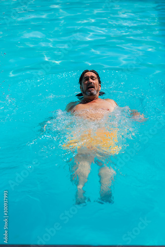 Vertical photo of a man swimming backwards in a pool