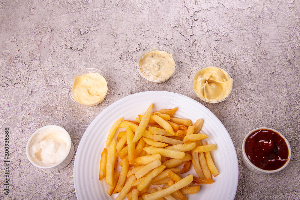 White plate of french fries chips potato and sauces on gry concrete background. top view. copy spacce White plate of french fries chips potato and sauces on gry concrete background. top view. copy spacce