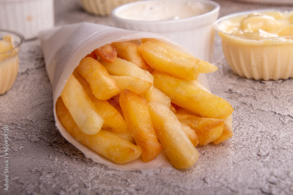 paper conus of french fries chips potato and sauces on gry concrete background. paper conus of french fries chips potato and sauces on gry concrete background.
