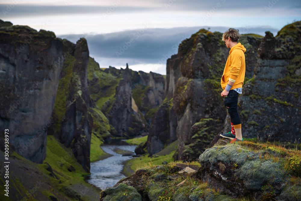 Young hiker standing at the edge of the Fjadrargljufur Canyon in Iceland