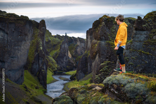 Young hiker standing at the edge of the Fjadrargljufur Canyon in Iceland