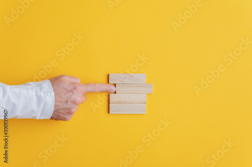 Businessman pushing the second peg from the top out of the stack of them