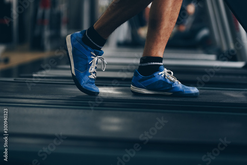 close up of man feet running on treadmill in the gym. concept of doing sport, healthy living, weight loss.