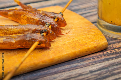 Dried mullet on a wooden Board with a mug of beer on the table. Fish and seafood cuisine. Tasty snack. photo