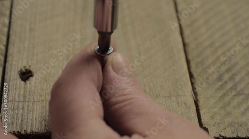 Hand using manual screwdriver to secure screw into wood photo