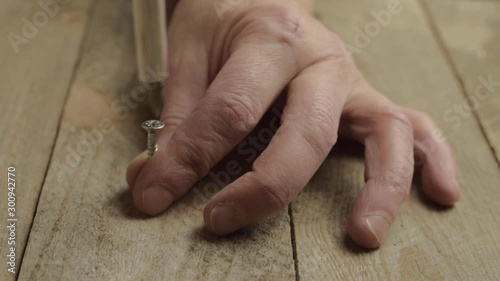 Hand using manual screwdriver to secure screw into wood photo