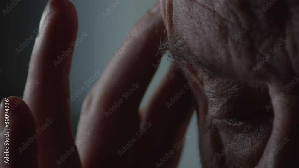 Adult man with headache rubs temple, extreme close-up of eye Adult man with headache rubs temple, extreme close-up of eye