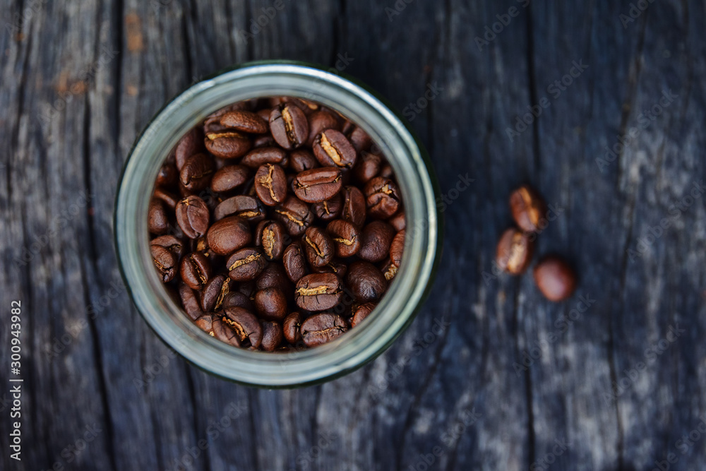 Fototapeta premium roasted coffee beans in glass containers on old wood table background, overhead view with copy space