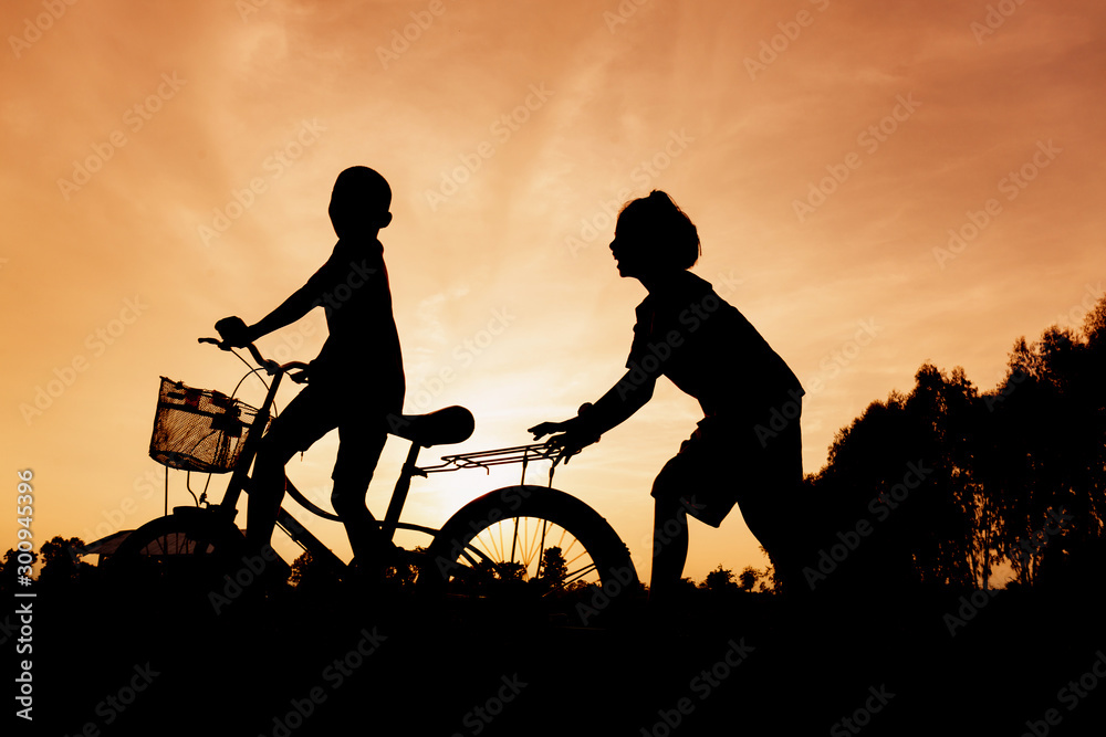 Silhouette of lifestyle children active playing bicycles on summer outside Silhouette of lifestyle children active playing bicycles on summer outside