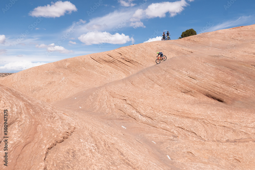 Son, mother and grandfather riding mountain bikes of singletrack in Moab, Utah