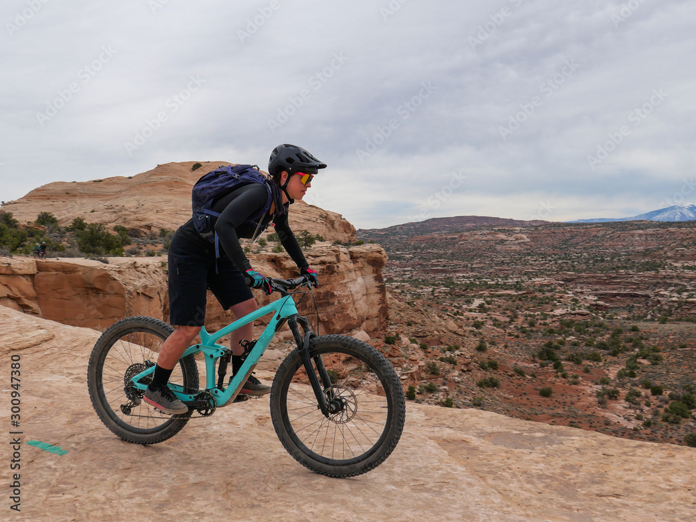 Young woman riding mountain bikes on singletrack in Moab, Utah