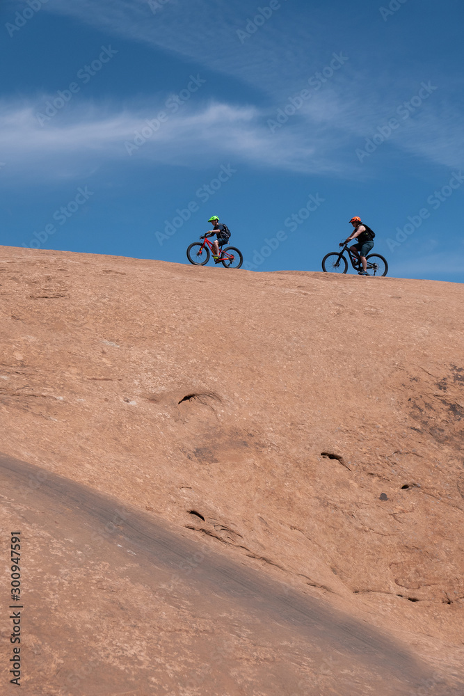 Son and mother riding mountain bikes of singletrack in Moab, Utah