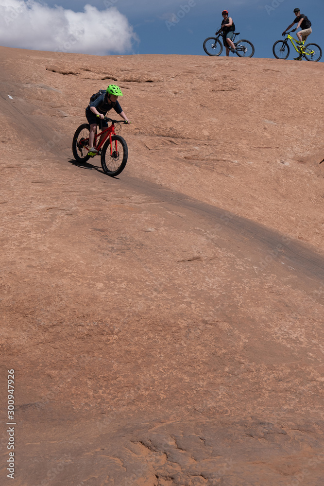 Son, mother and grandfather riding mountain bikes of singletrack in Moab, Utah