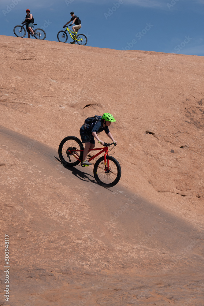 Son, mother and grandfather riding mountain bikes of singletrack in Moab, Utah