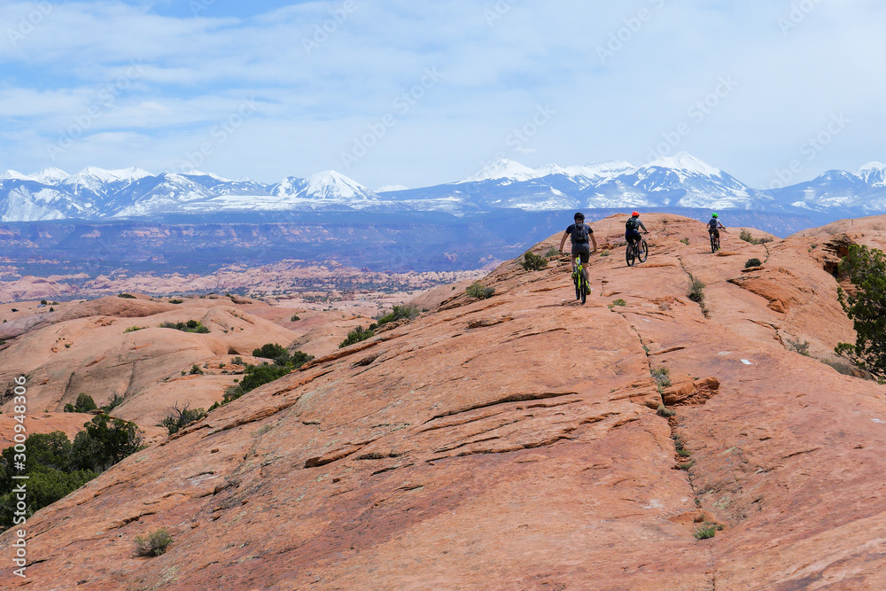 Son, mother and grandfather riding mountain bikes of singletrack in Moab, Utah