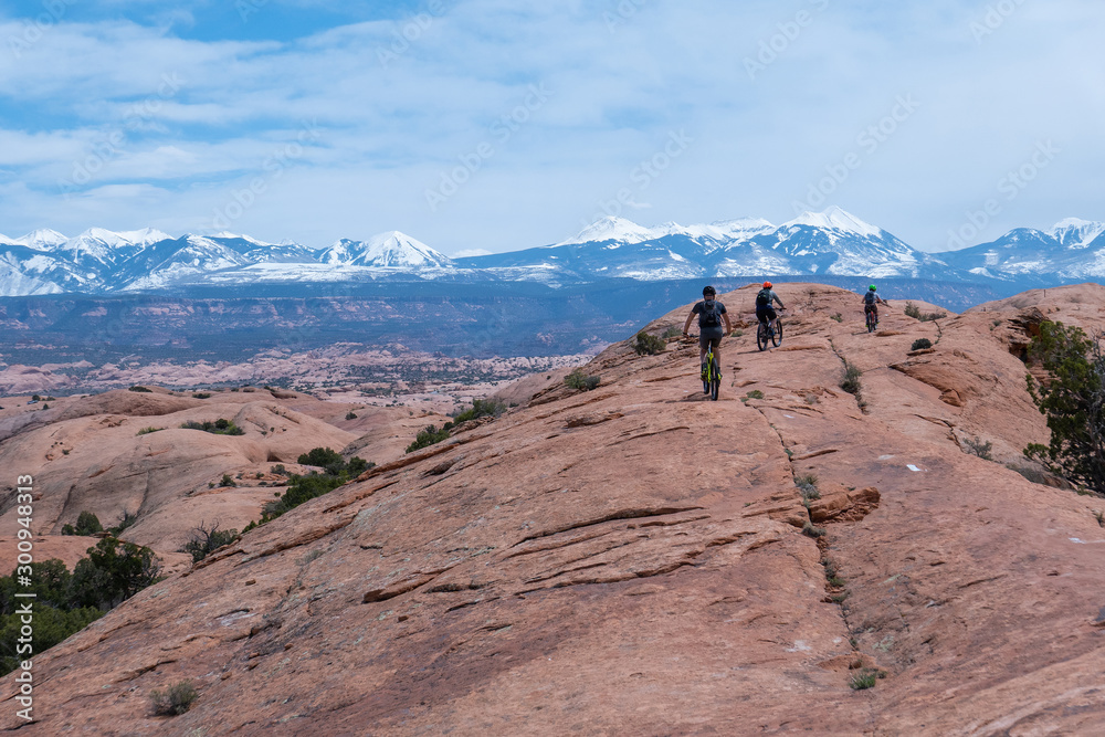 Son, mother and grandfather riding mountain bikes of singletrack in Moab, Utah