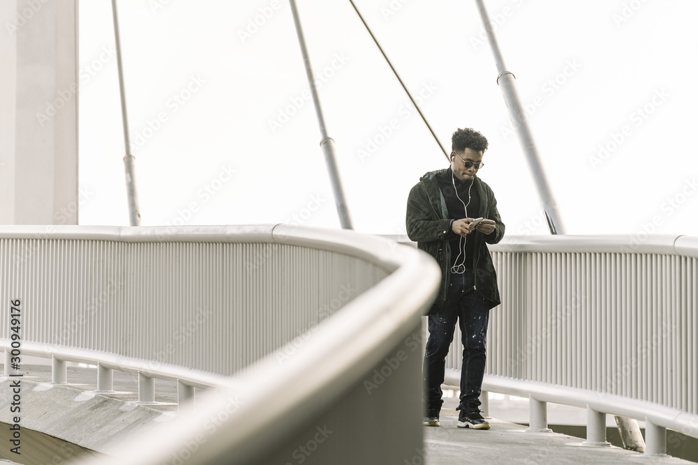 black man walks listening music at his smartphone