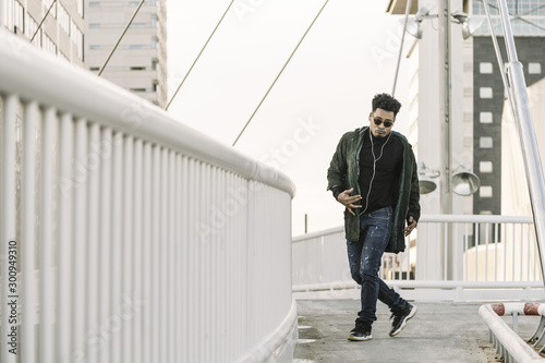 stylish black man with earphones dancing at city