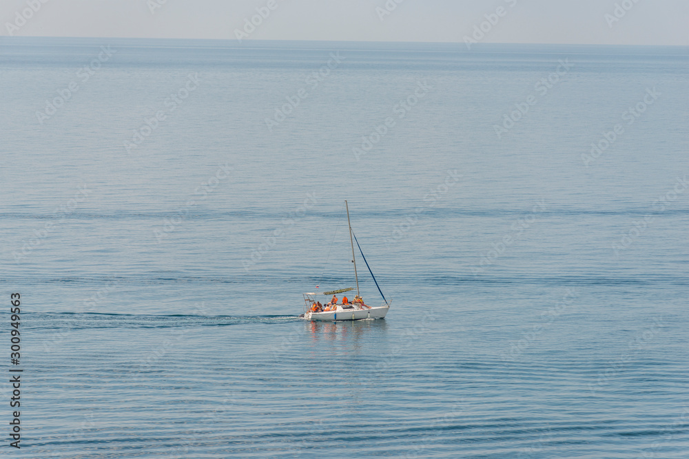 Aerial view on a white floating sailboat with people in it in the blue black sea Aerial view on a white floating sailboat with people in it in the blue black sea