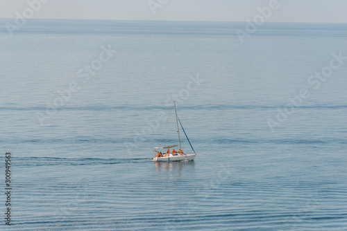 Aerial view on a white floating sailboat with people in it in the blue black sea © Pavel
