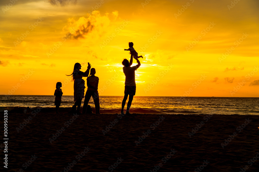 mother and father carry a child to take a photo on the beach in golden sunset.