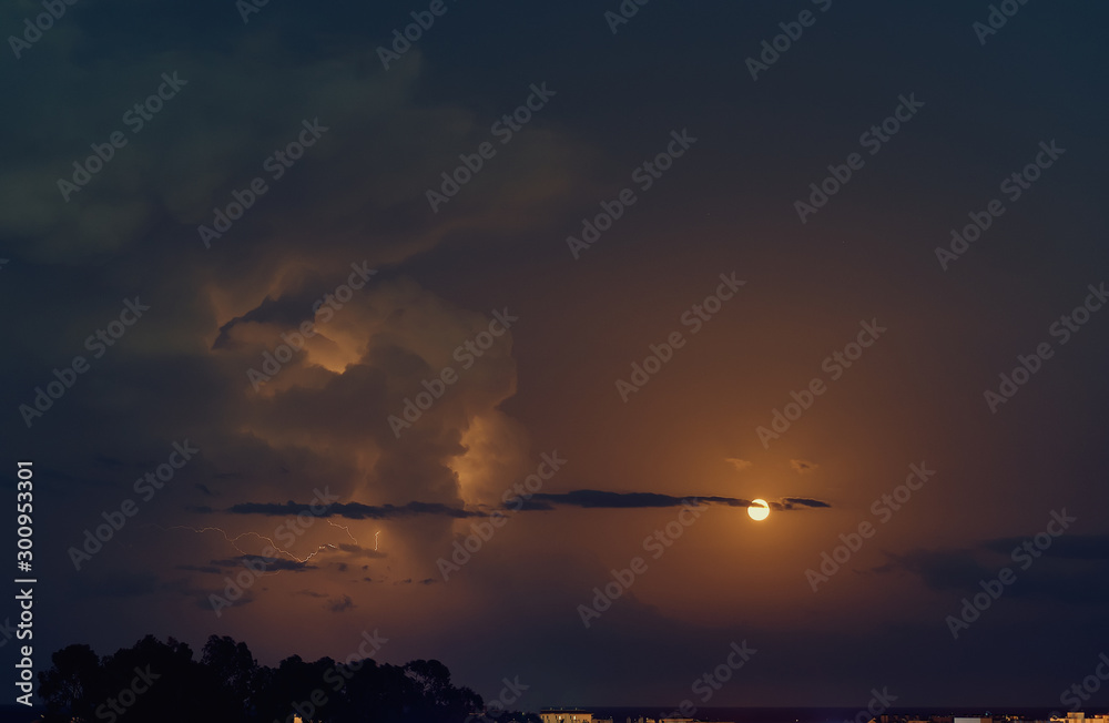 Picturesque bright blue, grey and orange colours cloudy sky with full moon and lighting during mucky weather, full frame nature background