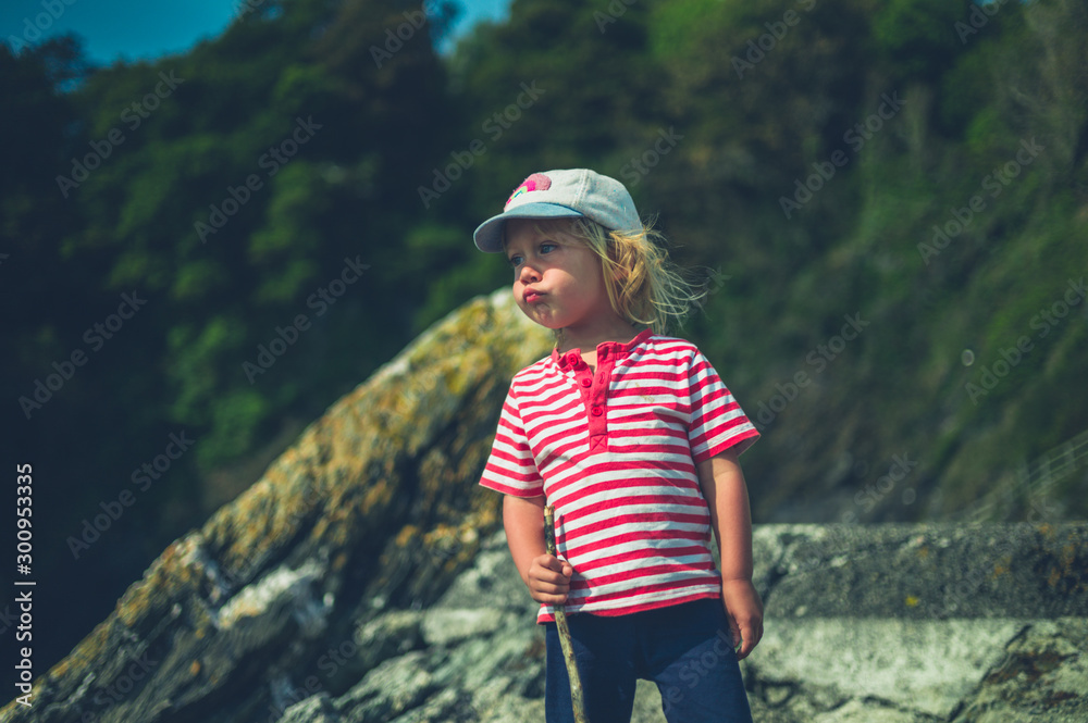 Little toddler standing by a rock with a stick Little toddler standing by a rock with a stick