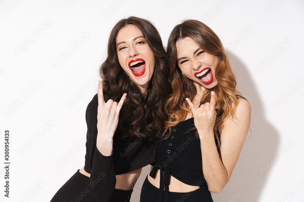 Image of joyful women in black outfit laughing and showing horn fingers Image of joyful women in black outfit laughing and showing horn fingers