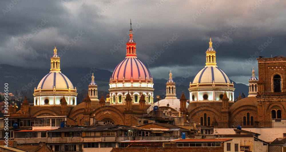 New Cathedral Domes in Cuenca, Ecuador are illuminated in the city flag colors for Independence Day, shown at dusk.
