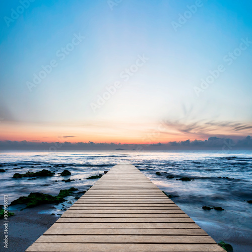 Wood bridge on the sea which has walk way for travel with beautiful sky and sunshine background.