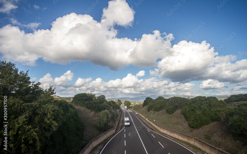 traffic on the highway with cars and lights moving, seen from above, with a beautiful panorama of fields and mountains and clouds