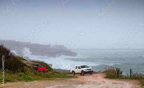 A huge ocean waves breaking on the coastal cliffs in at the cloudy stormy day. Breathtaking romantic seascape of ocean coastline. Peniche  Portugal.