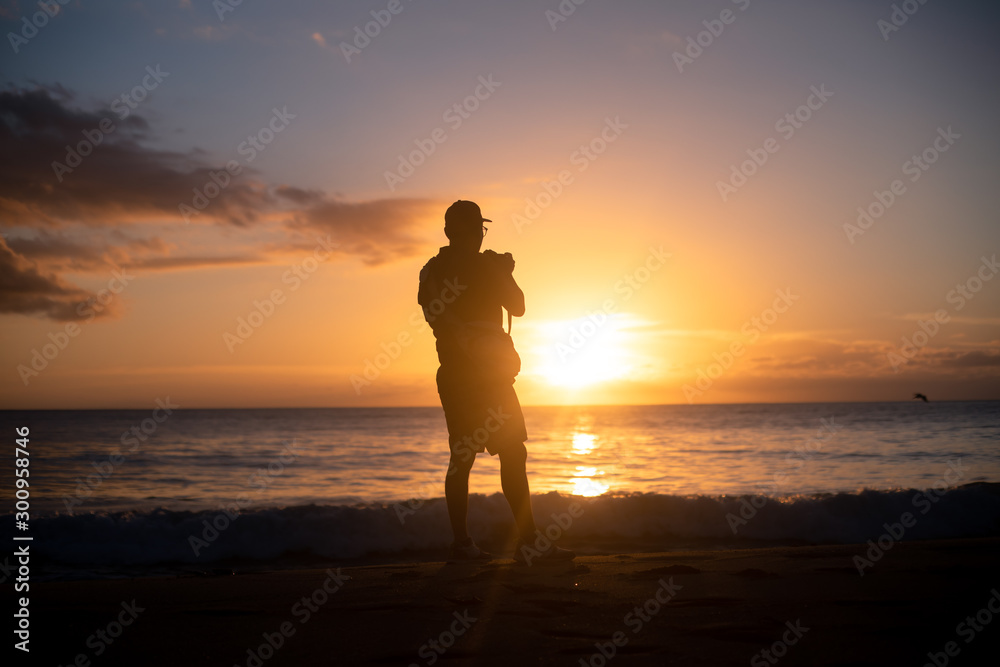 The silhouette of a male hobbyist photographer taking photos of a beautiful colorful sunset on the West Puerto Rico coast near Rincon