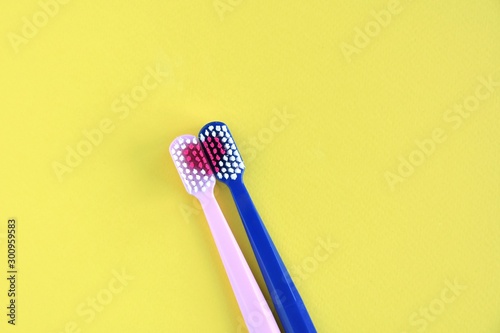 Toothbrush for personal healthcare dental care on yellow background.Two bright toothbrushes with red heart. Toothbrush for personal healthcare. St. Valentine s Day concept. Lovers toothbrushes
