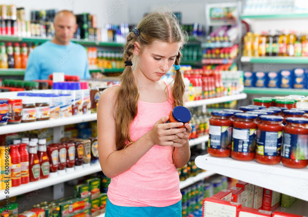 Tween girl choosing and buying food products at grocery shop