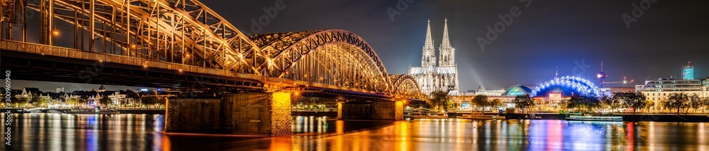 Panorama of the city of Cologne at night with Cologne Cathedral, Hohenzollern Bridge and Rhine river - obrazy, fototapety, plakaty 