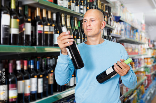 Portrait of male consumer looking bottle of red wine