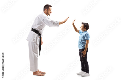 Man in karate kimono gesturing high-five with a boy