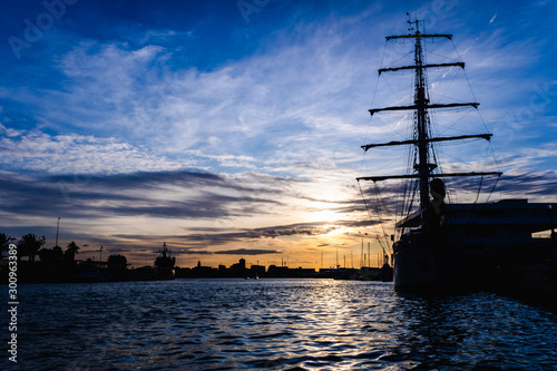 A classic sailboat moored to port in a beautiful sunset.