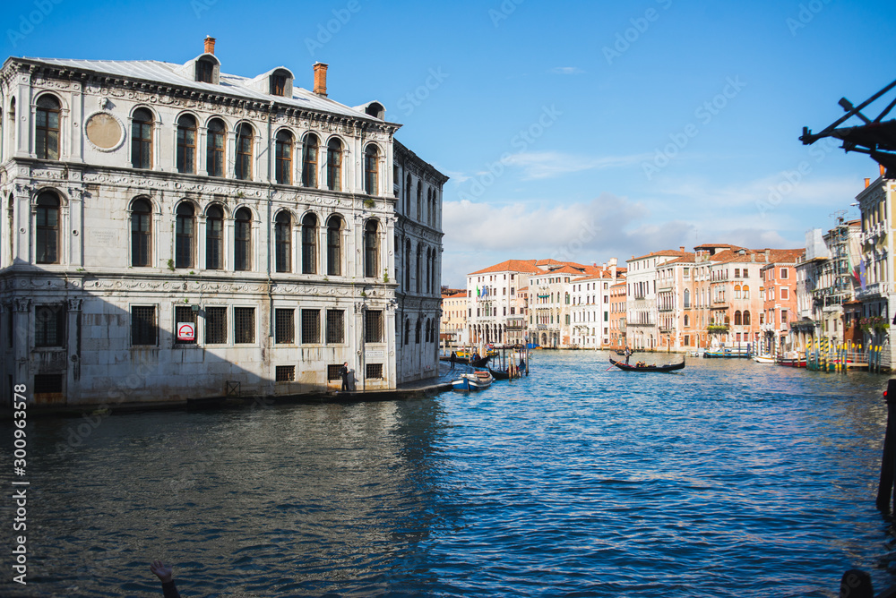View of the Grand Canal in Venice during sunset. Ttraditional gondolas and boats with passengers. Historic buildings.