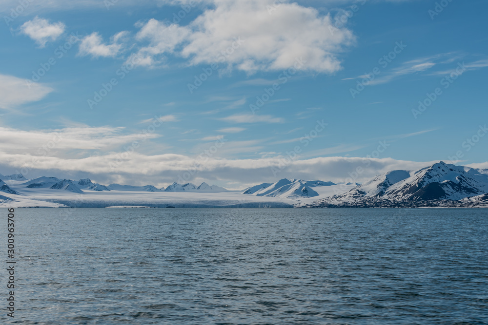 Snow covered mountains and a glacier by an arctic fjord in Svalbard